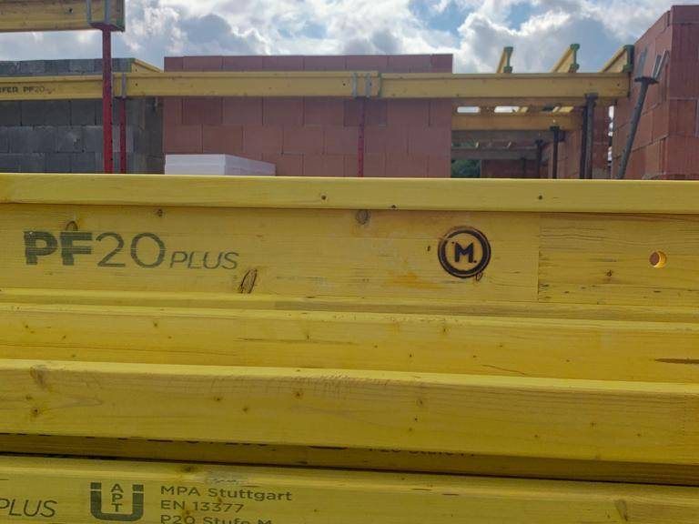 Gelbe Schalungsträger aus Holz gestapelt neben der Baustelle